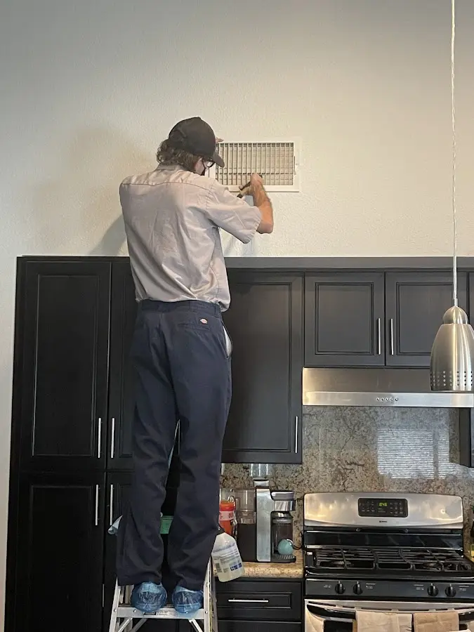 Technician inspecting an air vent during HVAC service in Rancho Santa Margarita